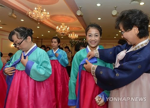 Multicultural families learn how to wear hanbok. (Yonhap)