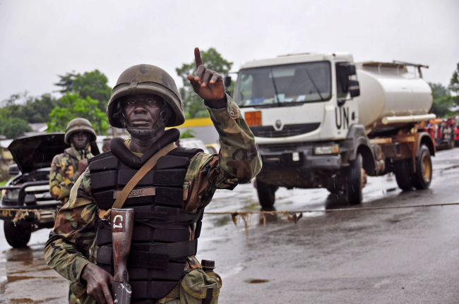 A Liberian soldier stops people at a security checkpoint set up to clamp down on travel due to the Ebola virus on the outskirts of Monrovia on Thursday.   AP-Yonhap