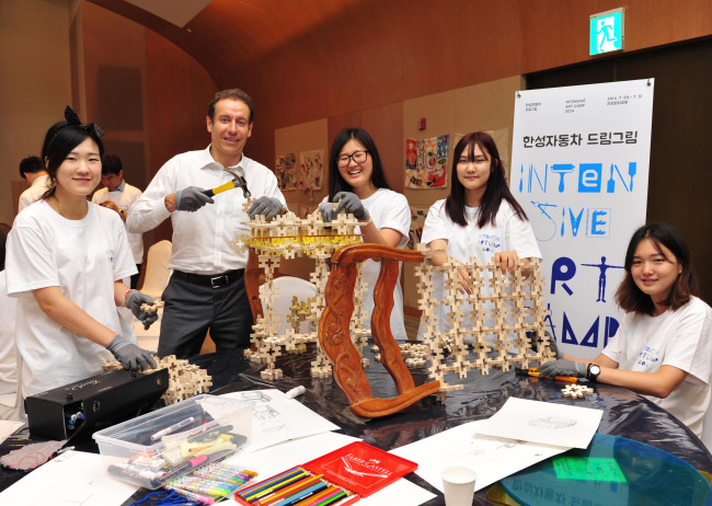 Han Sung Motor CEO Ulf Ausprung poses with students while making chairs using recycled materials during the Intensive Art Camp, part of the company’s Dream Gream Project, at the Konjiam Resort in Gyeonggi Province on July 30.   Han Sung Motor