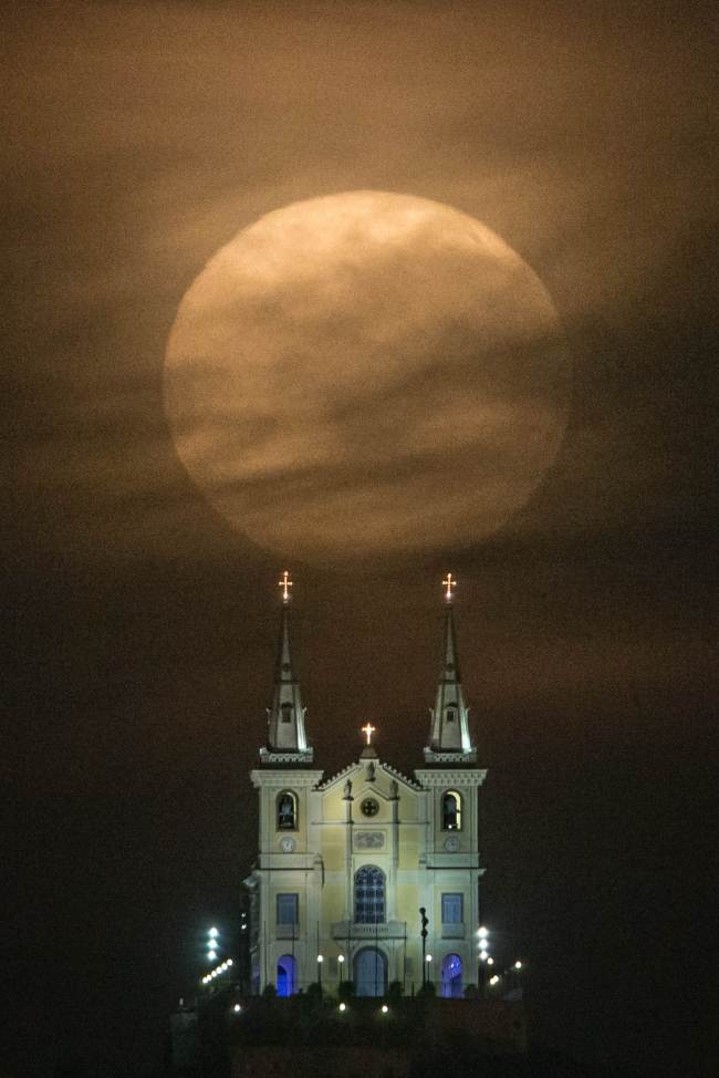 The full moon descends behind the Nossa Senhora da Penha Church in Rio de Janeiro, Brazil, Sunday. The “supermoon,” technically known as “perigee moon,” appears when the moon is closest to Earth in its orbit, making it appear much larger and brighter than usual.   AFP-Yonhap