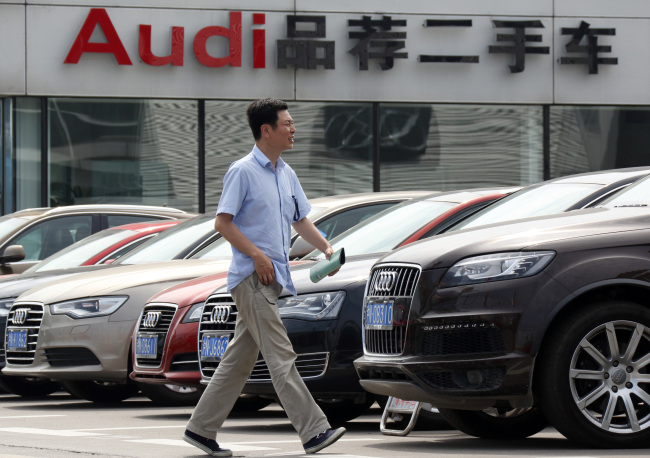 A man walks past Audi vehicles displayed at a dealership in Shanghai.   Bloomberg