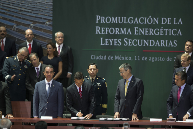 Enrique Pena Nieto (center), president of Mexico, signs legislation during a ceremony in Mexico City on Monday.   Bloomberg