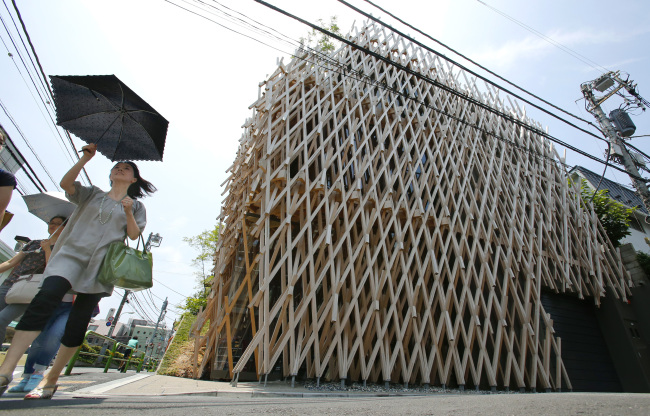 Women walk by Sunny Hills, also known as the “Pineapple House,” designed by Kengo Kuma, in Tokyo in mid-July.    AP
