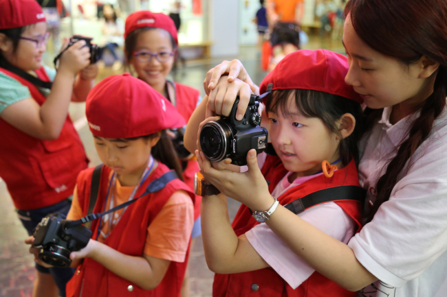 Children at POSCO Energy’s “Find my future job” event find out what it is like to be a photographer at Kidzania in Jamsil, southern Seoul, Tuesday.    POSCO Energy
