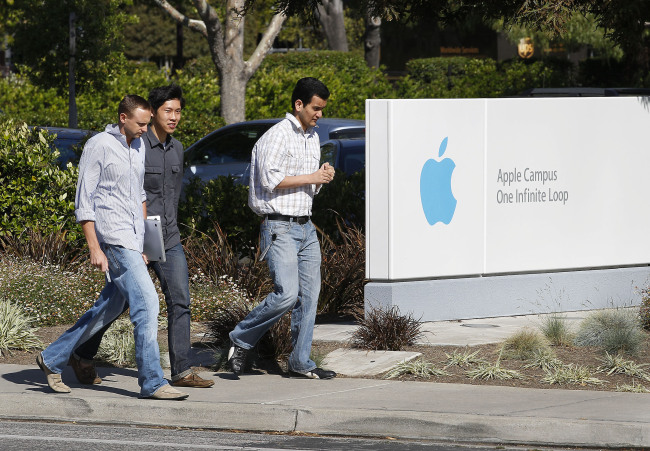 People walk by a sign outside Apple’s headquarters in Cupertino, California.   (Bloomberg)