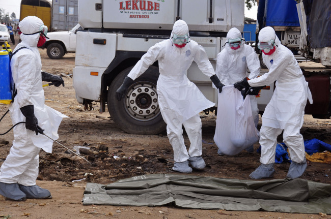Health workers carry the body of a man found in the street, who is suspected to have died from the Ebola virus, in Liberia’s capital city of Monrovia on Tuesday.   AP-Yonhap
