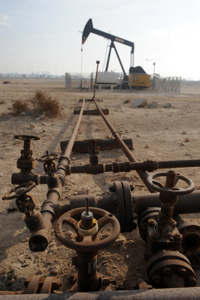 An oil pump operates near a valve assembly in the Awali oil field in Bahrain.    Bloomberg