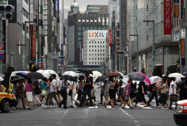 Pedestrians and shoppers cross a road in the Ginza district of Tokyo.    Bloomberg