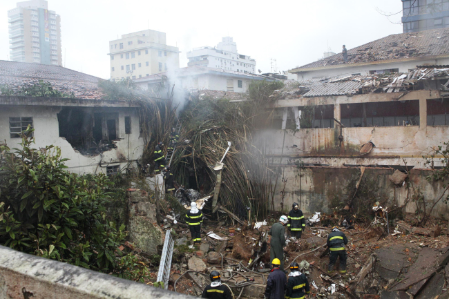 Firefighters work at the crash site of a small plane that was carrying Brazilian presidential candidate Eduardo Campos and several campaign officials in Santos, Brazil, Wednesday.   (AP-Yonhap)