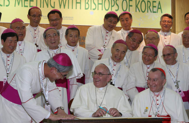 Pope Francis signs his name in the guest book at the Catholic Bishops’ Conference of Korea in Seoul on Thursday.   Park Hyun-koo/The Korea Herald