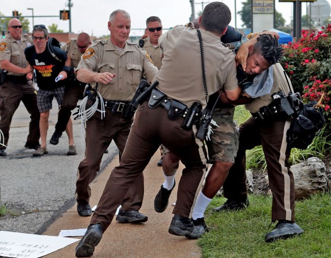 <YONHAP PHOTO-0286> Police tackle a man who was walking down the street in front of McDonald's on Monday, Aug. 18, 2014, in Ferguson, Mo. The man appeared to be walking past a group that had been assembled nearby and police were telling everyone to keep walking. Moments after he turned around and exchanged words with the police that he was just walking, police took him to the ground. Although there is no curfew in order tonight, police are strictly enforcing protestors to keep moving along the sidewalk or they are subject to arrest. (AP Photo/St. Louis Post-Dispatch, Laurie Skrivan)/2014-08-19 08:56:05/ <저작권자 ⓒ 1980-2014 ㈜연합뉴스. 무단 전재 재배포 금지.>
Police tackle a man who was walking down a street in Ferguson, Missouri, Monday. The man appeared to be walking past a group that had been assembled nearby while police were telling everyone to keep walking. (Related story on Page 6)   AP-Yonhap