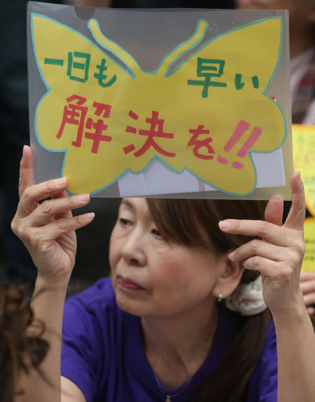 A Japanese activist holds a sign calling for a swift resolution to the issue of Japan’s sex slavery involving Korean and other Asian women during World War II at a weekly protest outside the Japanese Embassy in downtown Seoul on Wednesday.   Yonhap