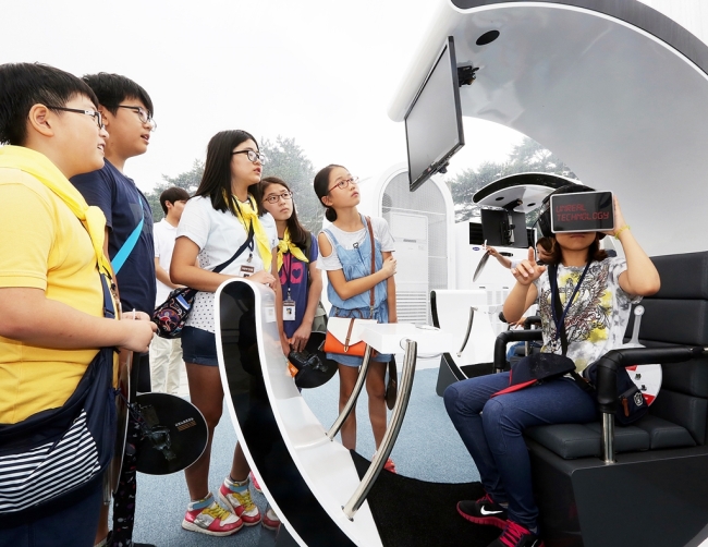 Children try out information technology devices Wednesday at T.um Mobile, a hands-on experience center established by SK Telecom in Yongsan, Seoul, to learn about the latest trends in the IT industry.    SK Telecom
