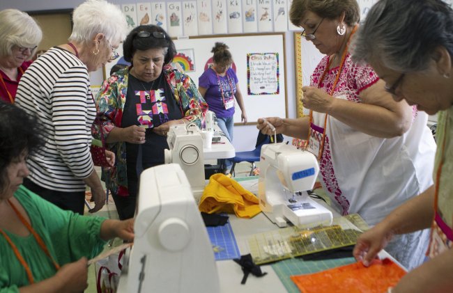 Gloria Molina (fourth from left) corrects Charlotte Lerchenmuller (third from left) and other quilters on proper stitching during a quilting workshop at Centro Estrella, Los Angeles, Aug. 2. (Los Angeles Times/MBR)