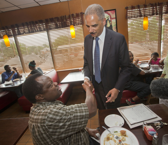 Attorney General Eric Holder (right) stops to shake hands with a patron at Drake’s Place Restaurant before his meeting with local community leaders in Ferguson, Missouri, Wednesday.   AP-Yonhap