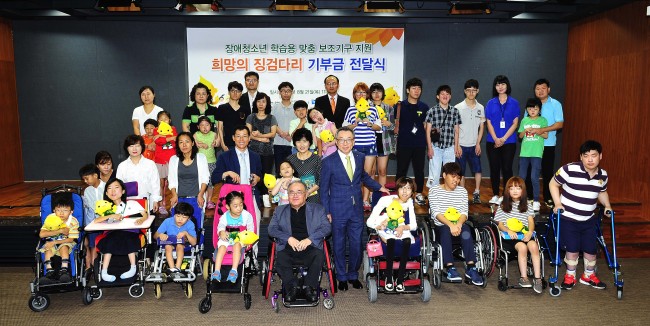 S-Oil senior vice president Cho Young-il (front row, sixth from left) poses with disabled youths from low-income families after providing them with learning aids at the firm’s Seoul office on Thursday.   S-Oil