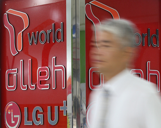 A pedestrian walks past an mobile phone shop.  (Yonhap)