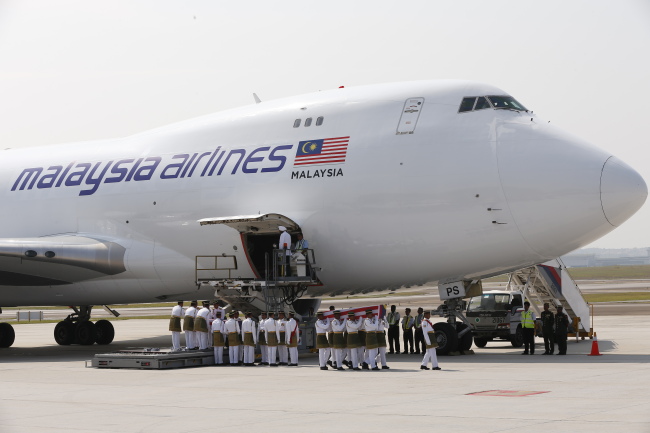 Malaysian army soldiers carry one of the bodies of the downed MH17 flight upon its arrival at Kuala Lumpur International Airport in Sepang, Malaysia, Friday.   AP-Yonhap