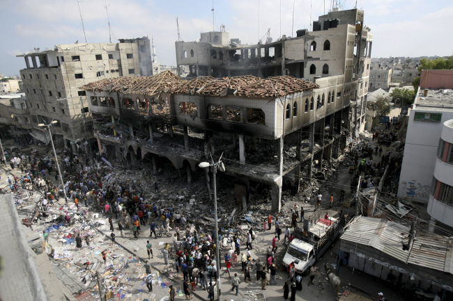 Palestinians inspect the damage of a commercial center after an Israeli air strike in Rafah in the southern Gaza Strip on Sunday.   AP-Yonhap