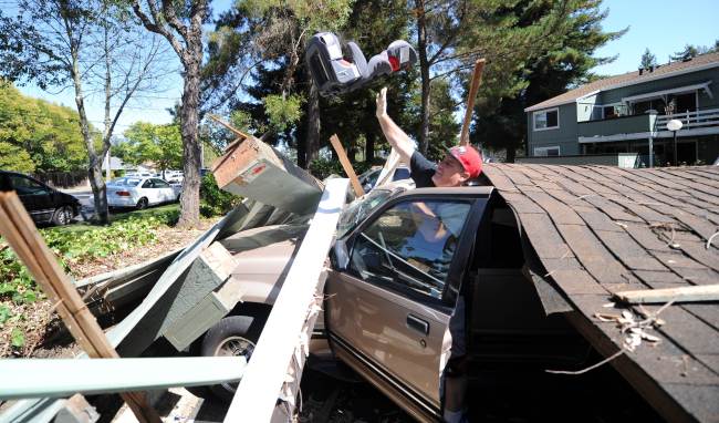 A man removes a child’s car seat from a vehicle trapped under a collapsed carport after an earthquake struck Napa, California, Sunday.   AFP-Yonhap