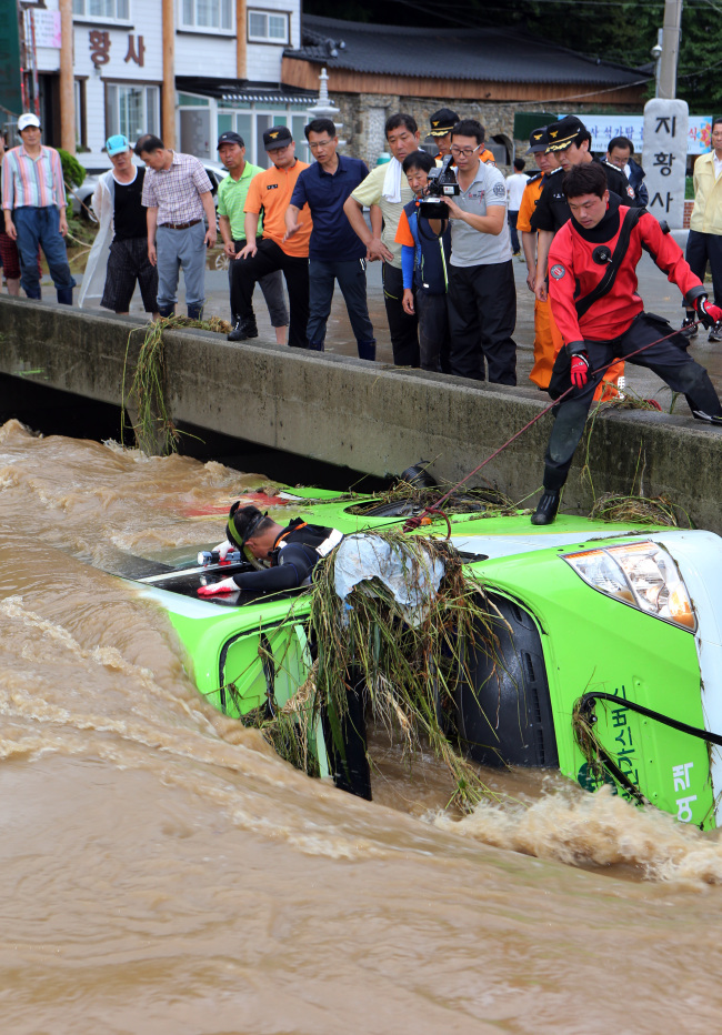 A destroyed bus drifts to a stop against a bridge in Changwon, South Gyeongsang Province, Monday.   Yonhap
