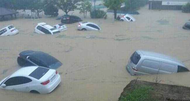 Cars float down a flooded road in Geumjeong-gu, Busan, on Monday after torrential rain hit the southeastern port city. (Related story, photo on Page 4)   Yonhap