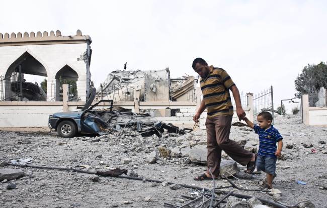 A Palestinian man walks with a child past the rubble of a mosque that was damaged in an Israeli air strike in Beit Lahia, Gaza Strip, Monday.   AFP-Yonhap