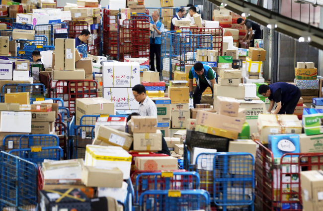 Delivery people sort out gift parcels for Chuseok at Korea Post’s distribution center in Seoul on Tuesday. This year the Chuseok holiday falls on Sept. 8.   Yonhap