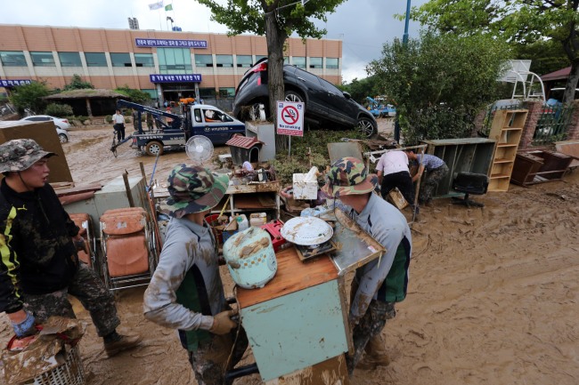 Civil servants and Army troops take part in cleanup efforts outside a local government office in Busan on Tuesday. The port city and other southwestern areas were hit by heavy rains of up to 130 millimeters per hour on Monday.   Yonhap