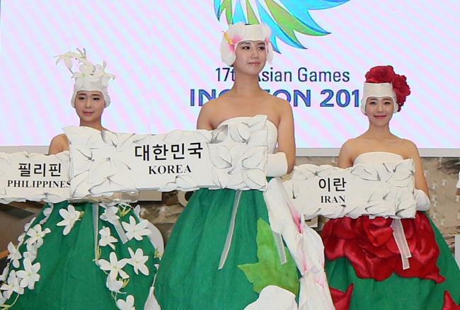 Three sign bearers for the 2014 Incheon Asian Games showcase their official outfits at the Museum of Modern and Contemporary Art in Seoul on Wednesday.   Yonhap