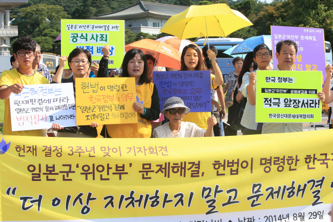Kim Bok-dong (seated), a victim of Japan’s wartime sexual slavery, and activists hold a rally to call on the Park Geun-hye administration to increase efforts to settle the “comfort women” issue, in front of Cheong Wa Dae on Friday.   Yonhap