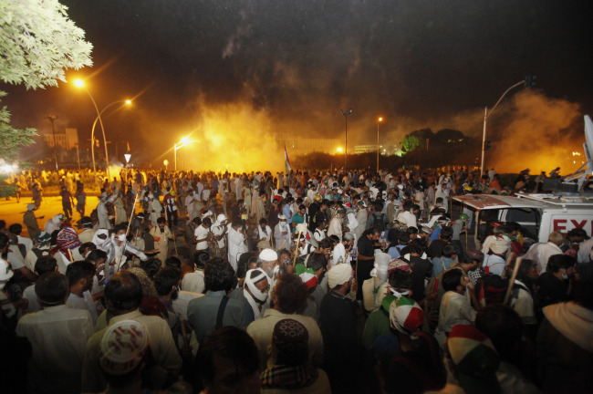 Pakistani protesters run during clashes near the prime minister’s home in Islamabad on Saturday.   AP-Yonhap