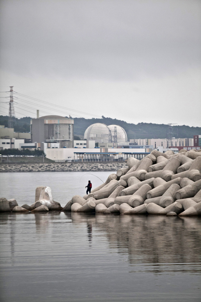 A man fishes near unit 1 (left) of the Wolseong Nuclear Power Plant Complex in Gyeongju. The reactor stopped power generation on Dec. 20, 2012, as its initial design lifespan expired. Korea Hydro & Nuclear Power Corp. is pushing for a license renewal by year-end.   Bloomberg