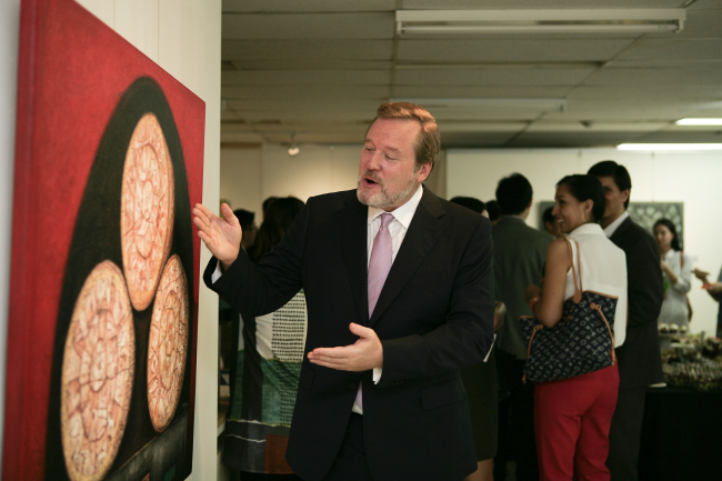 Ecuadorian Ambassador to South Korea Nicolas Trujillo gestures toward a painting by Hernan Illescas during the opening reception of the “Symbols of Dreams” exhibition at Gallery Bellarte in Seoul on Thursday. (Ecuadorian Embassy)