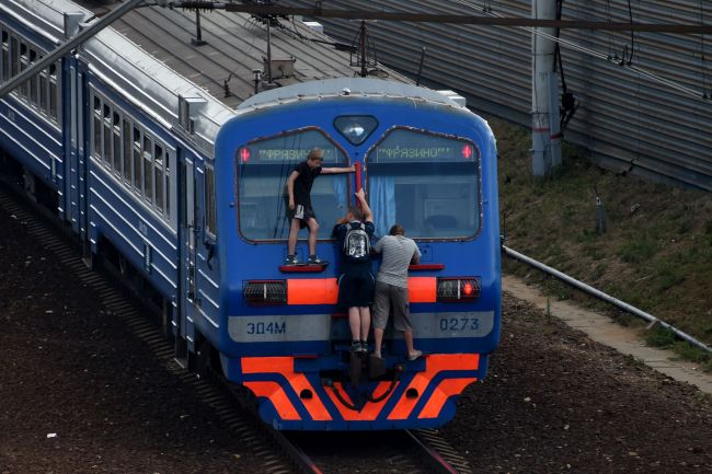 Men cling to the end of a train near the Losinoostrovskaya station in a suburb of Moscow. (AFP-Yonhap)