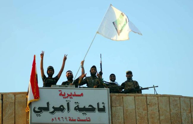 Members of the Iraqi Shiite militia “Peace Brigades” flash the victory sign on a government building in Amerli town, north of Baghdad, Tuesday.   EPA-Yonhap