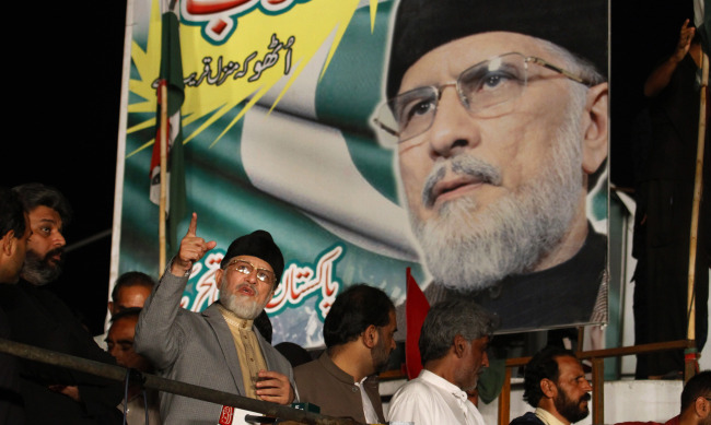Pakistan’s fiery cleric Tahir-ul-Qadri (second from left) gestures while delivering his speech during a protest in Islamabad on Wednesday.   AP-Yonhap