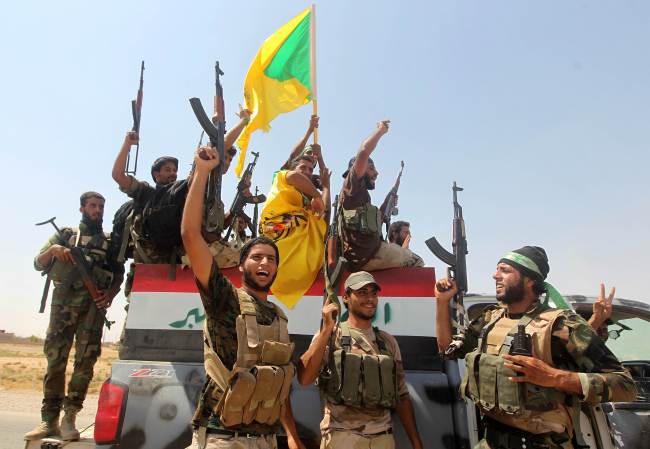 Iraqi Shiite fighters raise their weapons as they celebrate pushing back Islamic State militants on the road between Amerli and Tikrit on Wednesday.  AFP-Yonhap