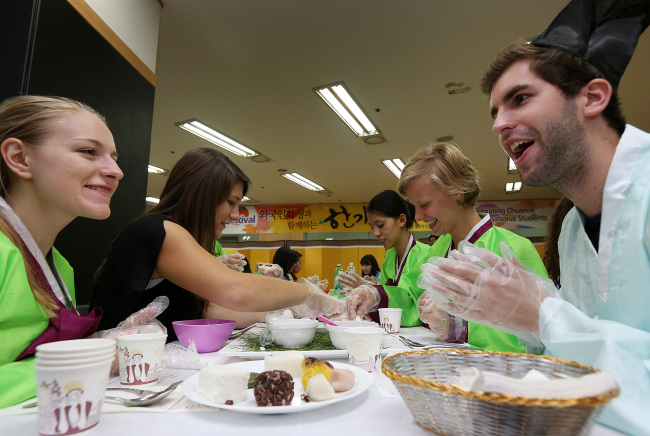 International students at Sungkyunkwan University in Seoul on Friday participate in the making of songpyeon, or Korean stuffed rice cakes, in celebration of the Chuseok holiday.   Yonhap