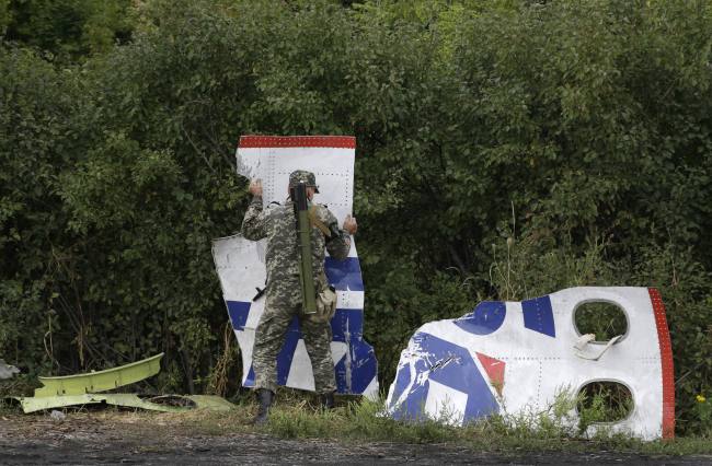 A pro-Russian rebel picks up pieces of the Malaysia Airlines Flight 17 plane near the village of Rozsypne, eastern Ukraine, Tuesday.   AP-Yonhap