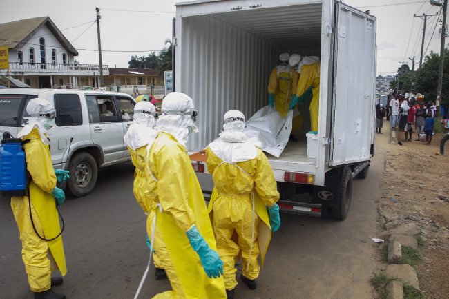 Liberian health care workers on an Ebola burial team collect the body of an Ebola victim in Paynesville on the outskirts of Monrovia on Tuesday.   EPA-Yonhap