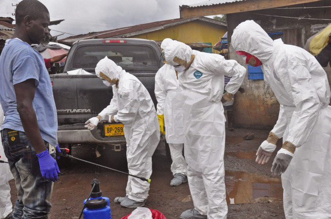 Health workers remove their protective clothes after carrying the body of a woman who they suspect died from the Ebola virus in an area known as Clara Town in Monrovia on Wednesday.   AP-Yonhap