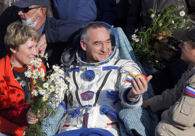 Russian cosmonaut Alexander Skvortsov (center) holds an apple as he talks with search-and-rescue team members after the Soyuz TMA-12M space craft landed near the city of Zhezkazgan, Kazakhstan, Thursday.   AP-Yonhap