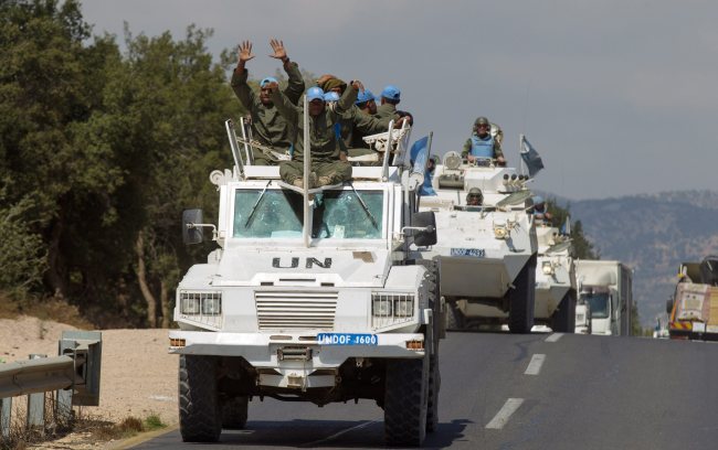 U.N. troops wave from their vehicles as they leave Syria and cross into Israel from the northern part of the Israeli-Syrian border near the Syrian village of Jubata Al Khashab in the Golan Heights on Monday.   EPA-Yonhap