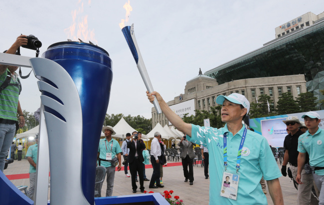 Lee Ho-yeon, a member of the Incheon Asian Games steering committee, lights the torch at Seoul Plaza two days before the event kicks off.  The torch arrived in the host city of Incheon later in the day. After a 36-day pilgrimage through 17 cities in South Korea, the flame reached the city two days before the opening ceremony. The torch will be left overnight in the port city for the next two days before completing the final leg of its 6,000-kilometer journey to Incheon Asiad Main Stadium. (Related stories, photos on Page 19)   Yonhap