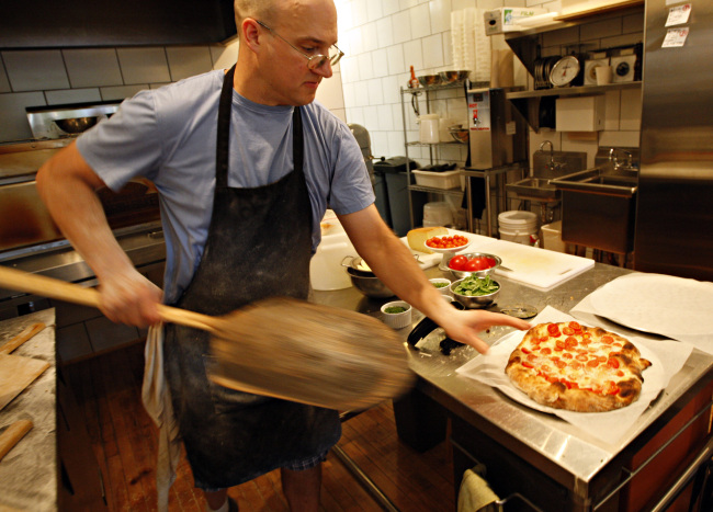 A chef pulls a pizza from the ovens at a restaurant in Andersonville, Illinois. MCT