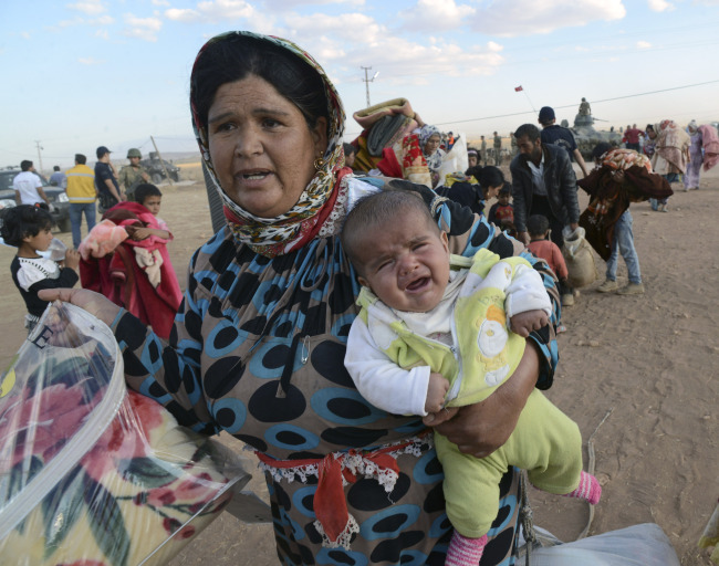 Syrian refugees gather at the border in Suruc, Turkey, Saturday.    AP-Yonhap