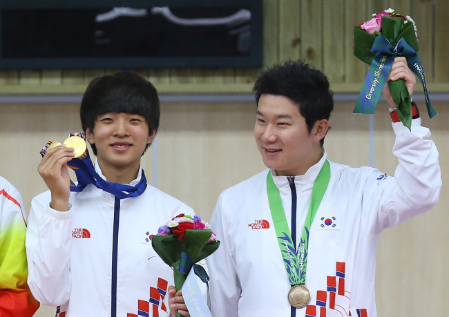 Korean shooting gold medalists Kim Cheong-yong (left) and Jin Jong-oh celebrate during the medals ceremony for the men’s 10-meter air pistol team competition at the 17th Asian Games at Ongnyeon International Shooting Range in Incheon on Sunday.   Yonhap