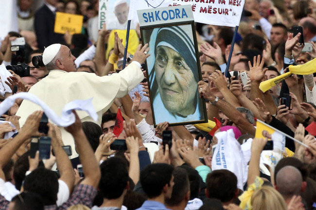 Pope Francis reaches for a poster of Mother Teresa as he is driven through the crowd in Tirana, Sunday.   AP-Yonhap