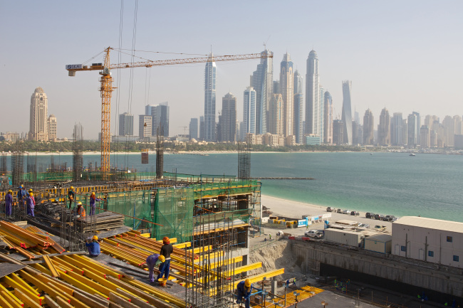 Construction workers build a waterfront apartment block on Palm Jumeirah island in Dubai.   Bloomberg